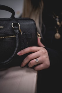 Close-up of luxurious rose gold accents on a Lumina handbag resting on a marble table.