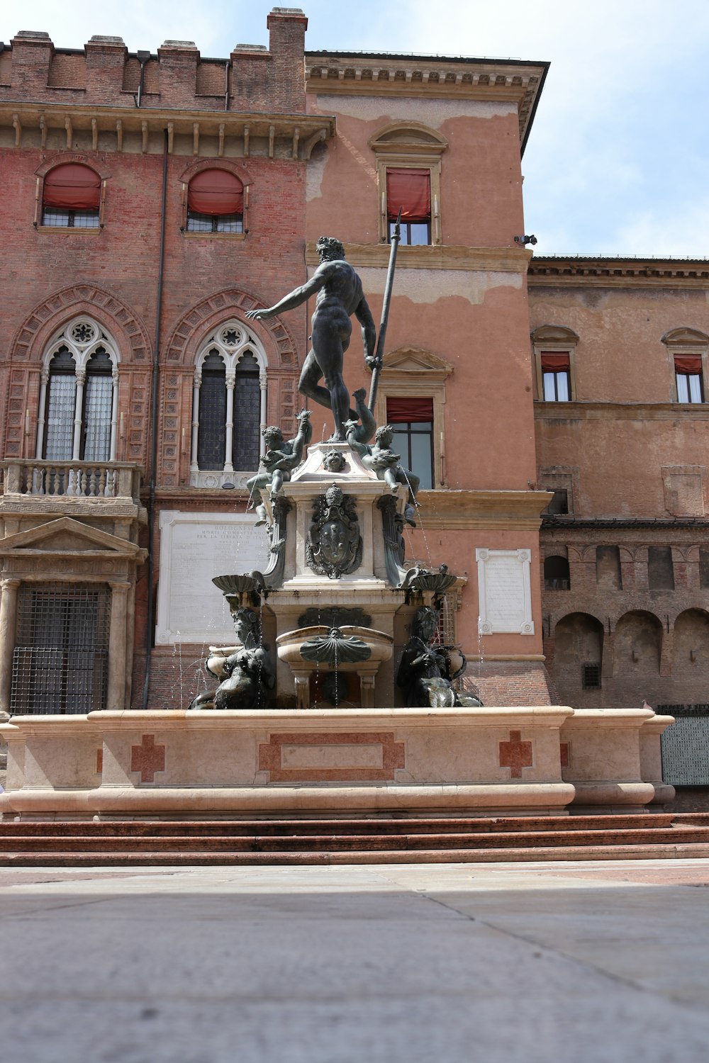 eine Statue einer Person, die einen Speer vor einem Gebäude hält