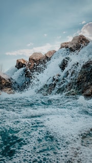 a body of water with rocks and a large waterfall