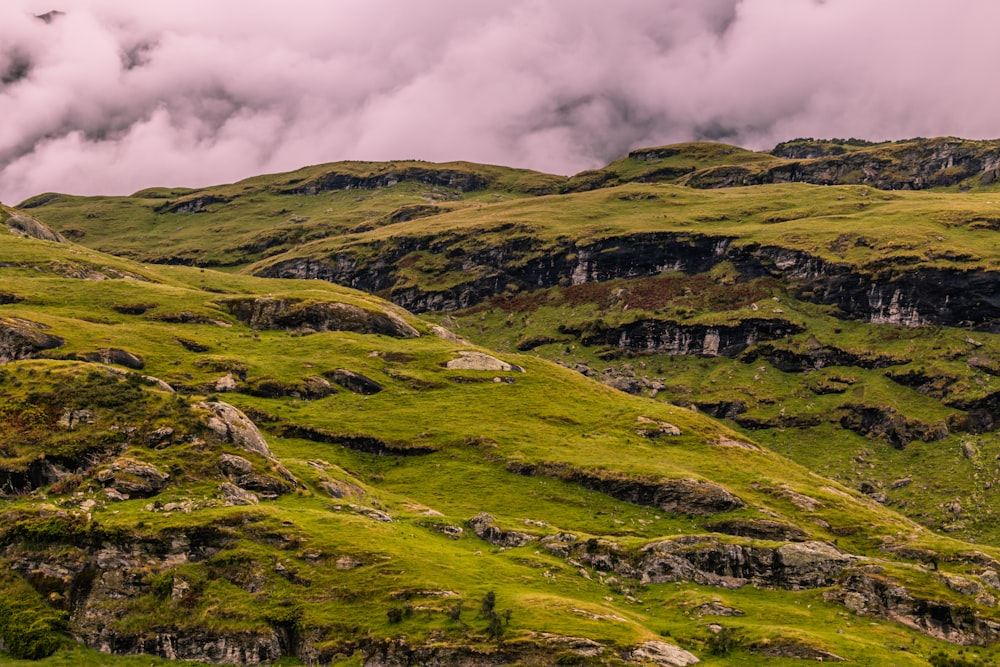 a grassy hill with a cloudy sky