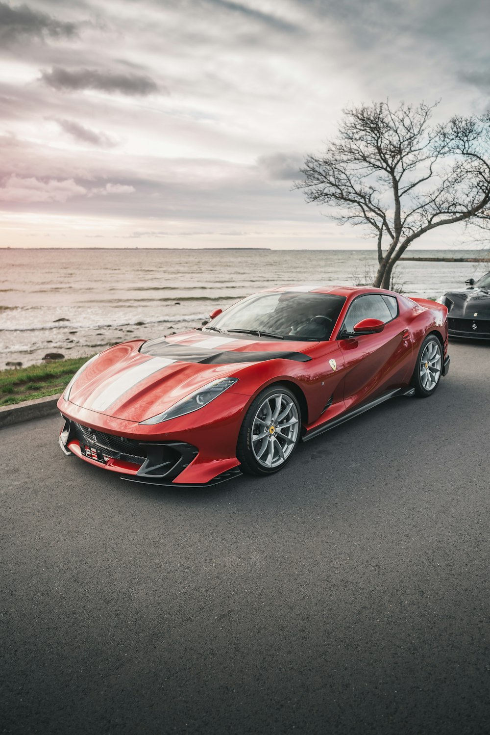 a red sports car parked on a road by a body of water