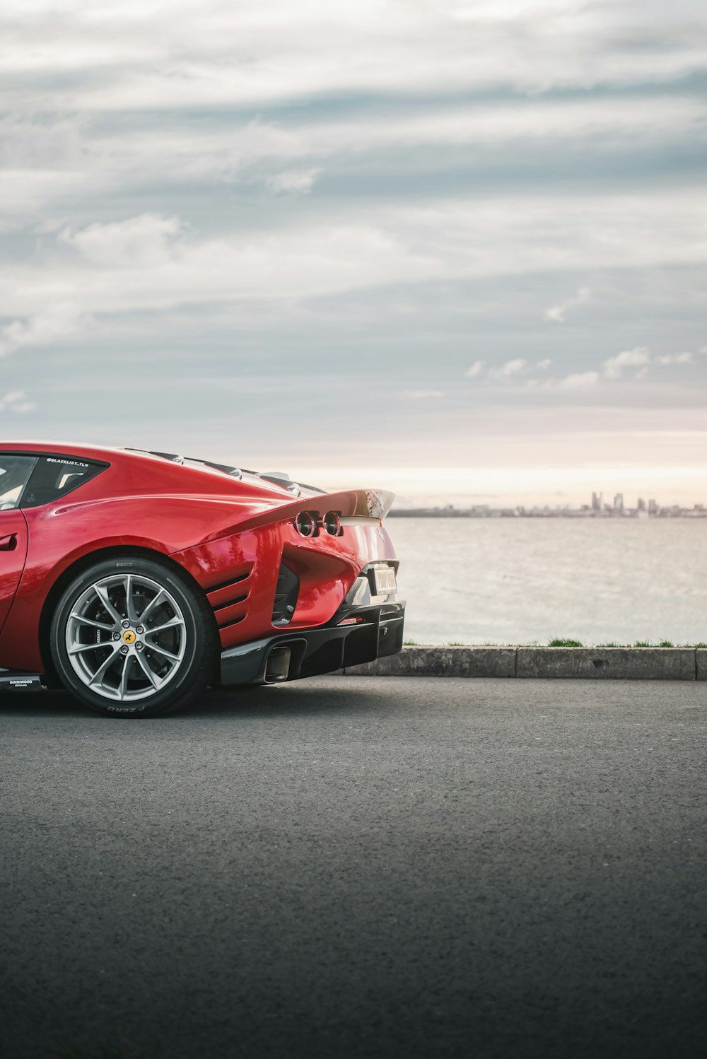 a red sports car parked on a road by a body of water