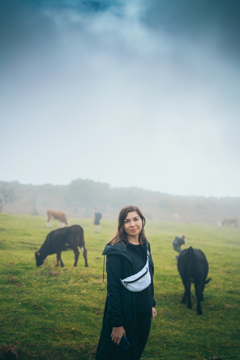 a person standing in a field with cows