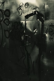 Dark graffiti-covered metal surface with abstract shapes and scribbles, creating a gritty urban atmosphere.