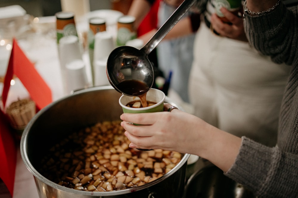 a person pouring a drink into a cup of coffee