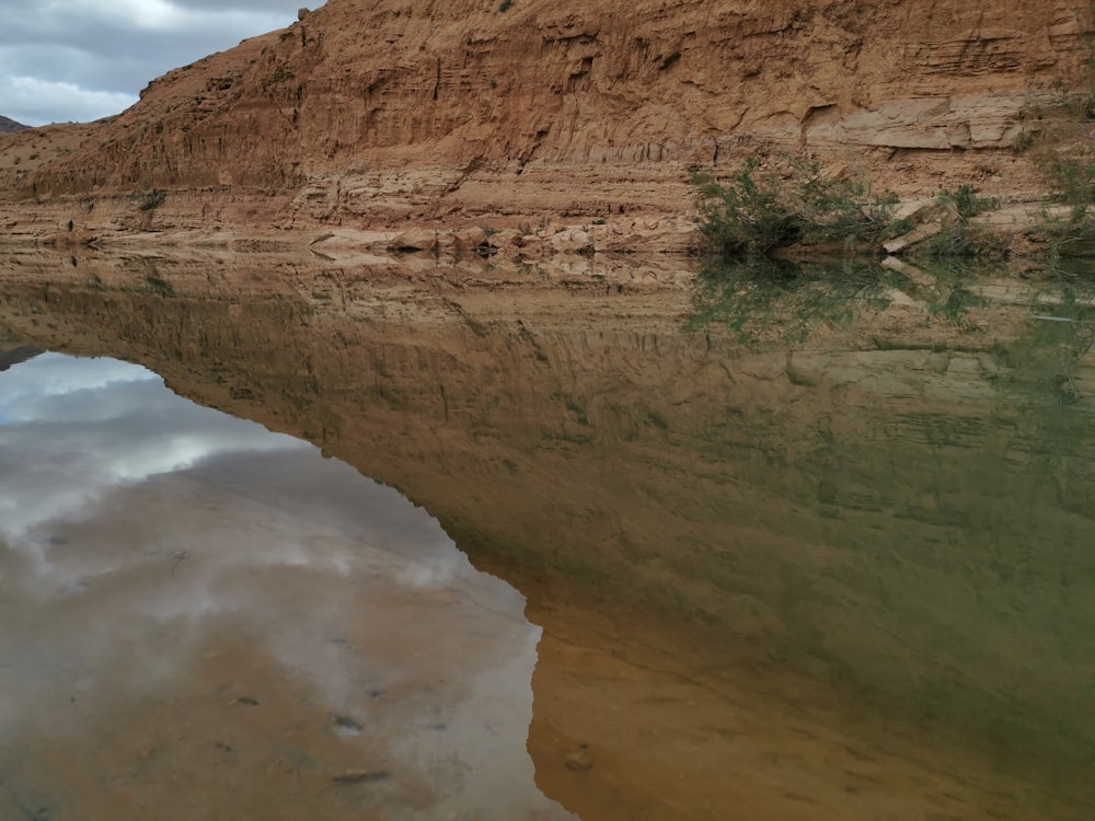 a body of water with a rocky cliff in the background