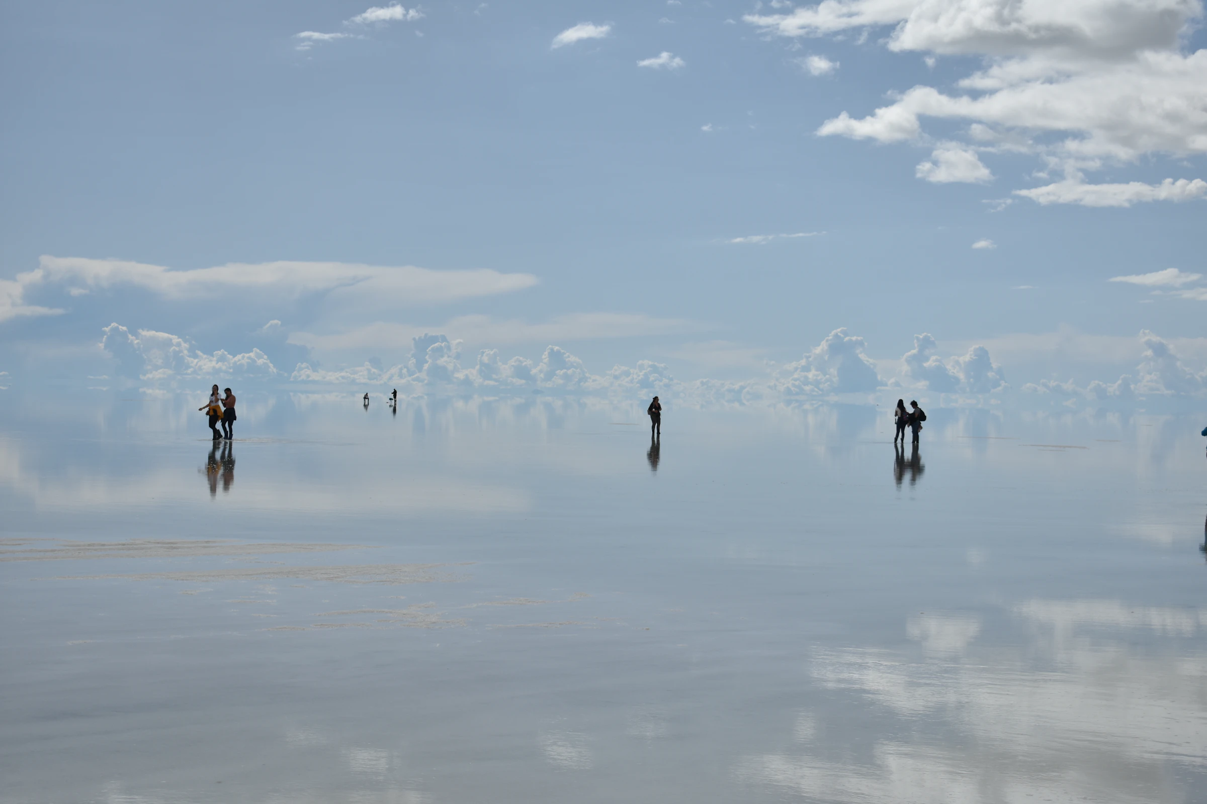 Personas caminando sobre el espejo de agua del salar