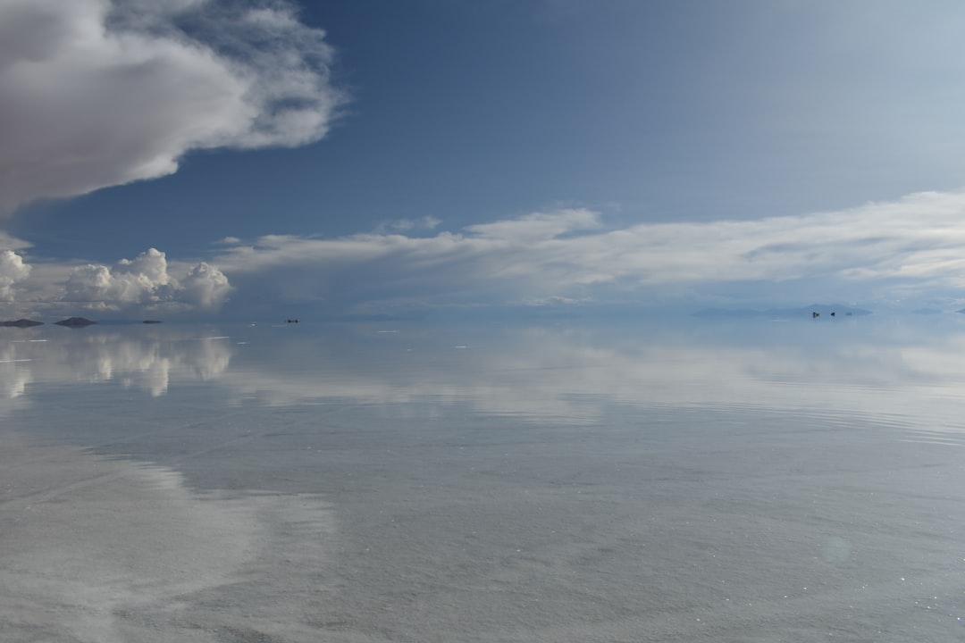 a body of water with clouds above it,