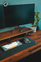 Side view of a modern desk setup featuring a plant, notebook, and a high-end keyboard.