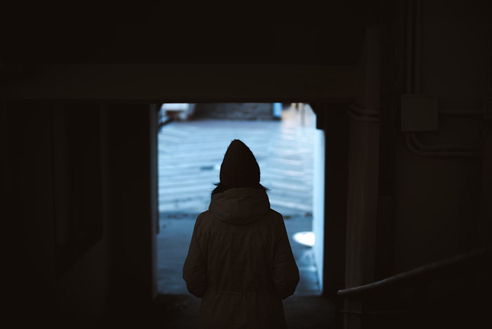 a woman in a white coat is walking down a dark hallway