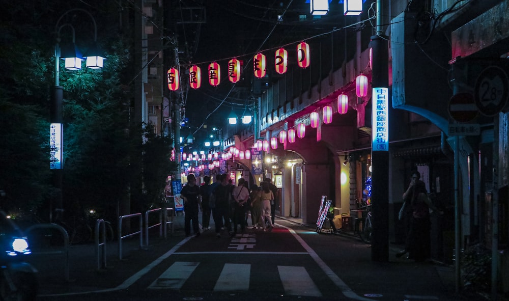 a group of people walking on a street at night