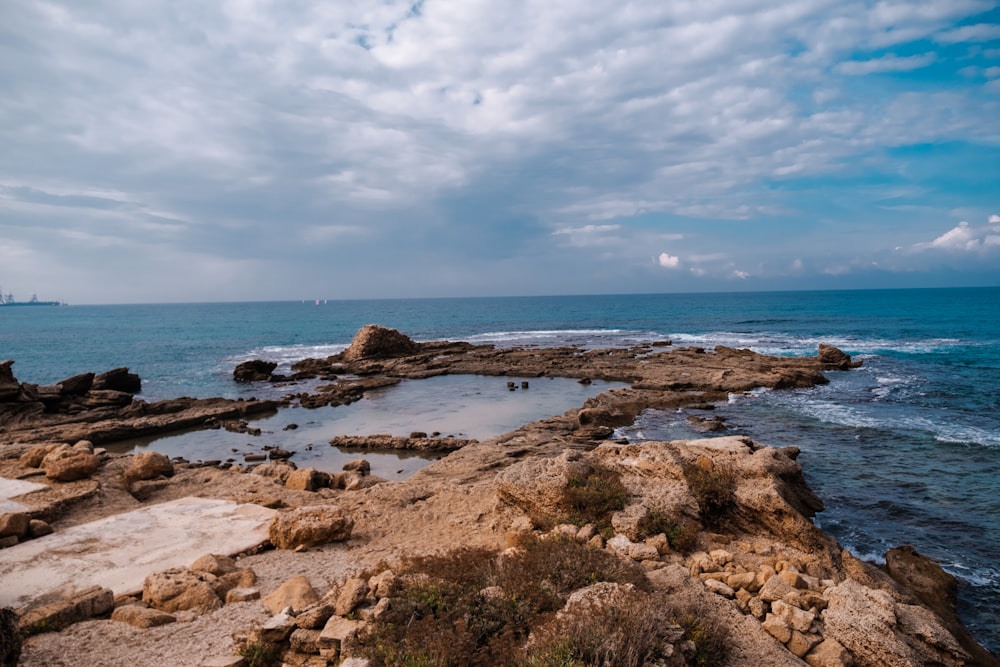 a rocky beach with a body of water in the background