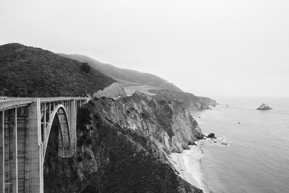 a cliff side with a body of water and a bridge