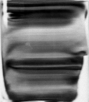 Blurry, distorted black and white image with horizontal lines running across. The overall appearance suggests motion or manipulation of a portrait, possibly resembling a face but indiscernible due to the abstraction.
