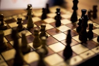 A chess creator smiling while explaining tactics in front of a camera with soft neutral background.
