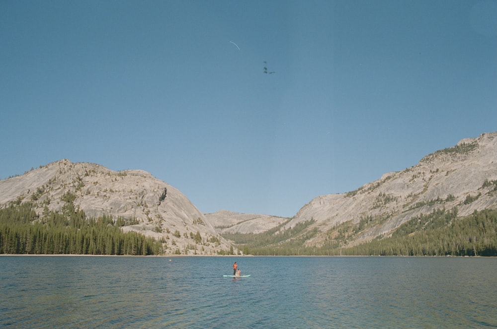 a person in a boat in a lake with mountains in the background