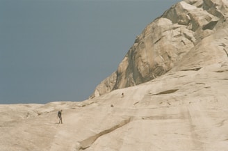 A small group of climbers learning rope handling on a sunlit natural rock face.