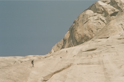 A small group of climbers learning rope handling on a sunlit natural rock face.