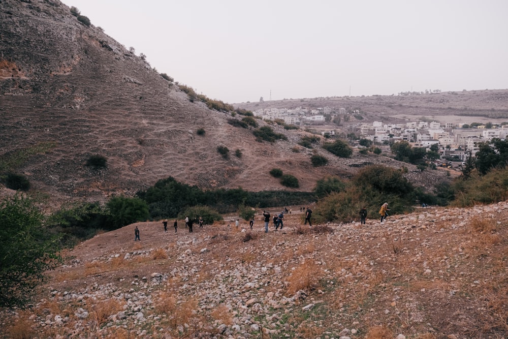 a group of people walking on a dirt path in a hilly area