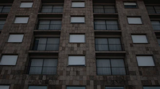 Exterior view of a building with warm natural stone and metal railings