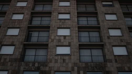 Exterior view of a building with warm natural stone and metal railings