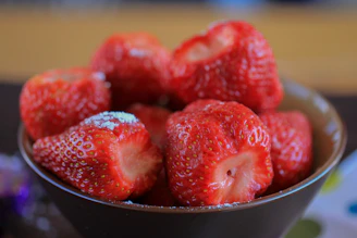 A bowl of bright red strawberries swirled with creamy white topping