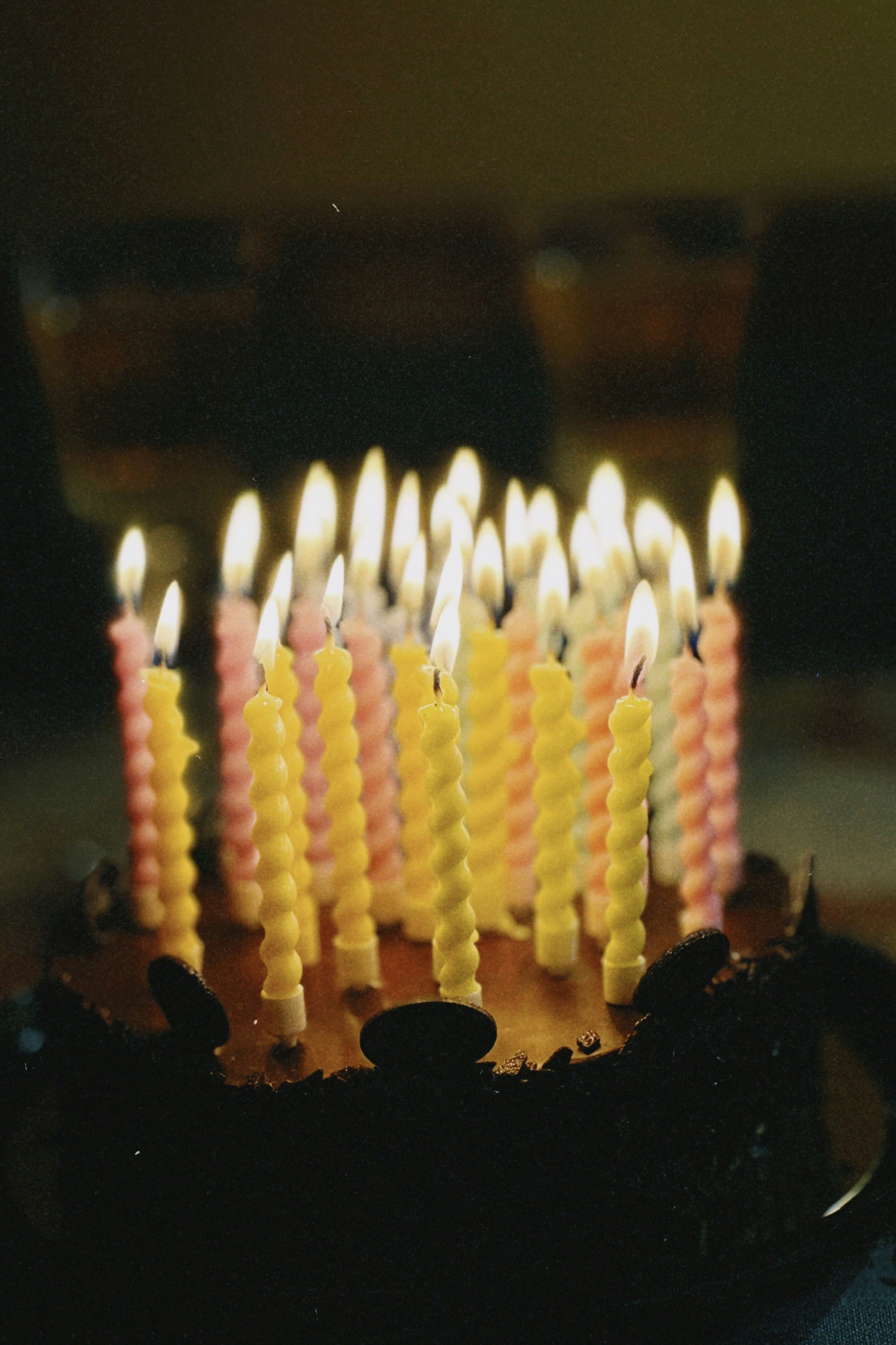 Birthday cake with candles and colorful balloons, warm celebratory lighting, dark rich background