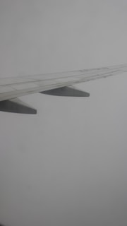 A sleek, minimalistic illustration of an airplane wing against a clear sky.