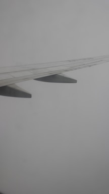 A sleek, minimalistic illustration of an airplane wing against a clear sky.