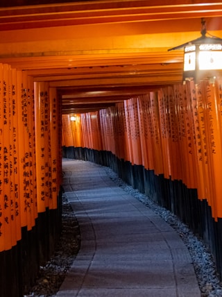 a long hallway with gold curtains with Fushimi Inari-taisha in the background