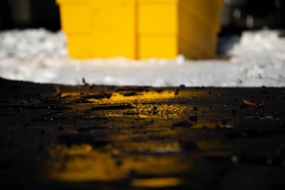 A bag of bc icemelt resting against a snow-covered curb.