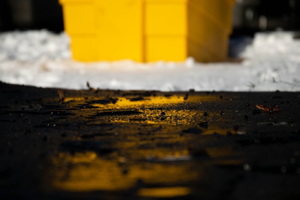 A bright yellow skip bin being delivered to a residential driveway on a sunny day.