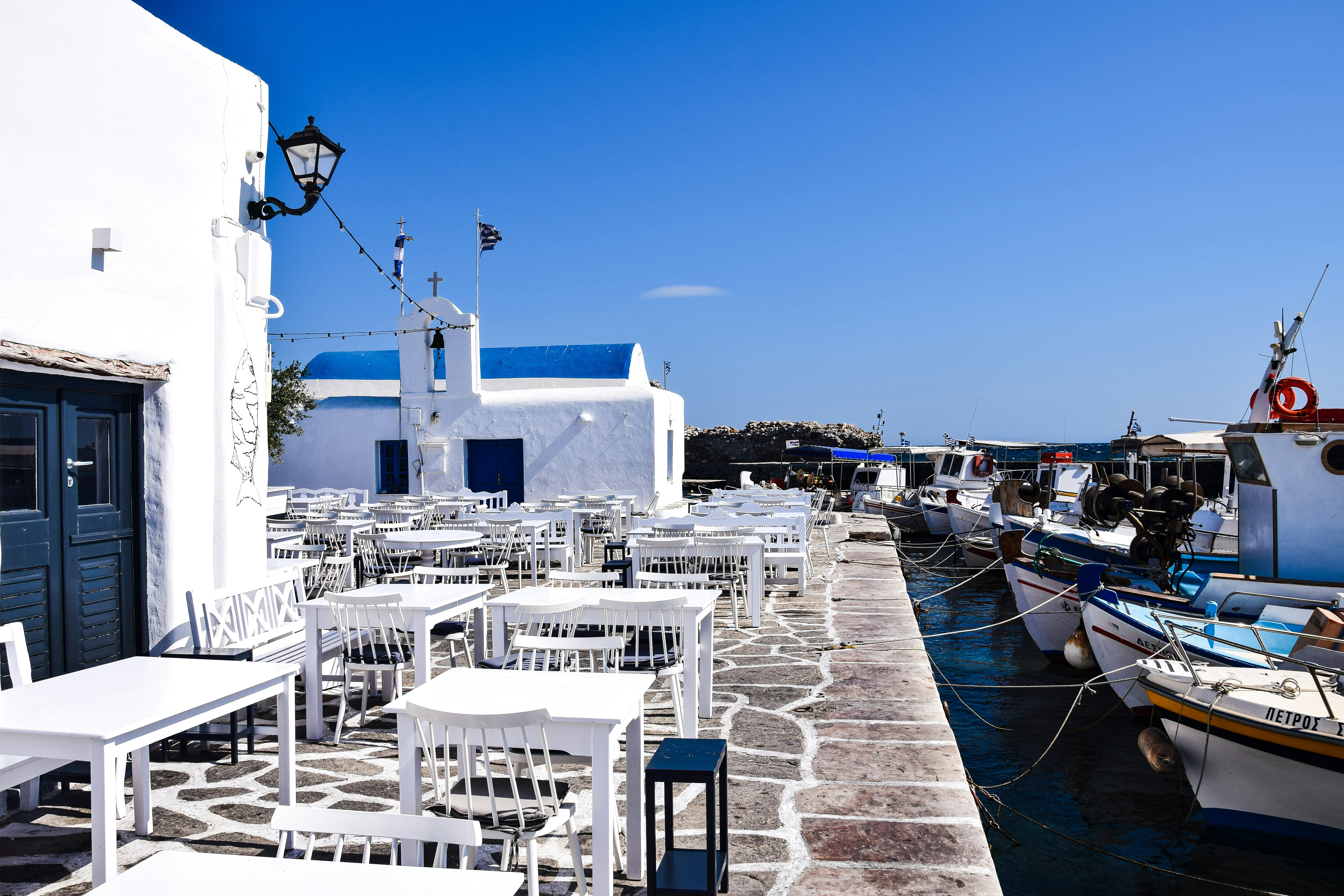 a row of tables and chairs on a dock, Paros, Greece.