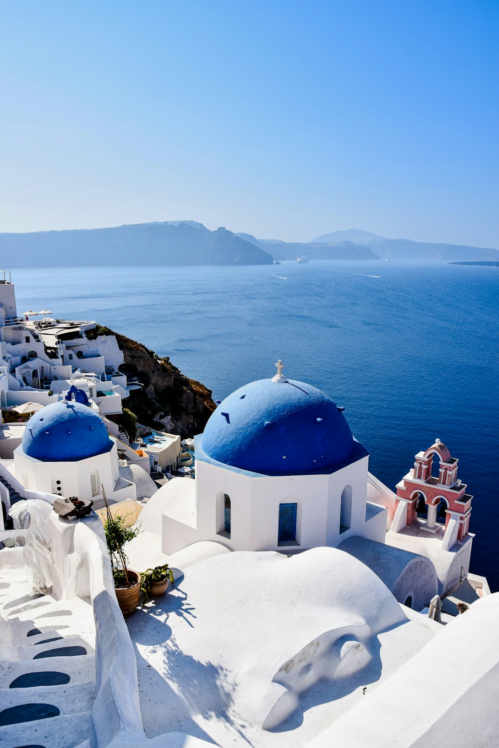 a white building with blue domes and a blue roof by the water