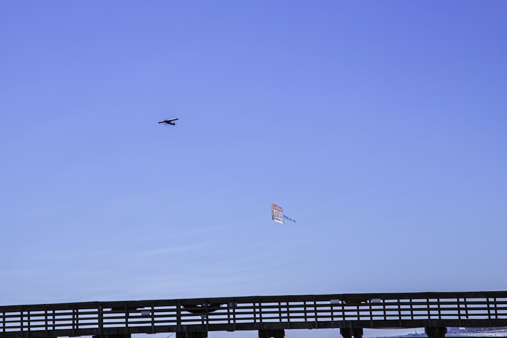 a plane flying over a bridge with a kite in the air