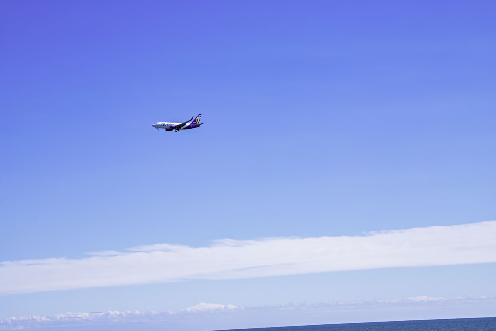 an airplane flying over the ocean on a clear day