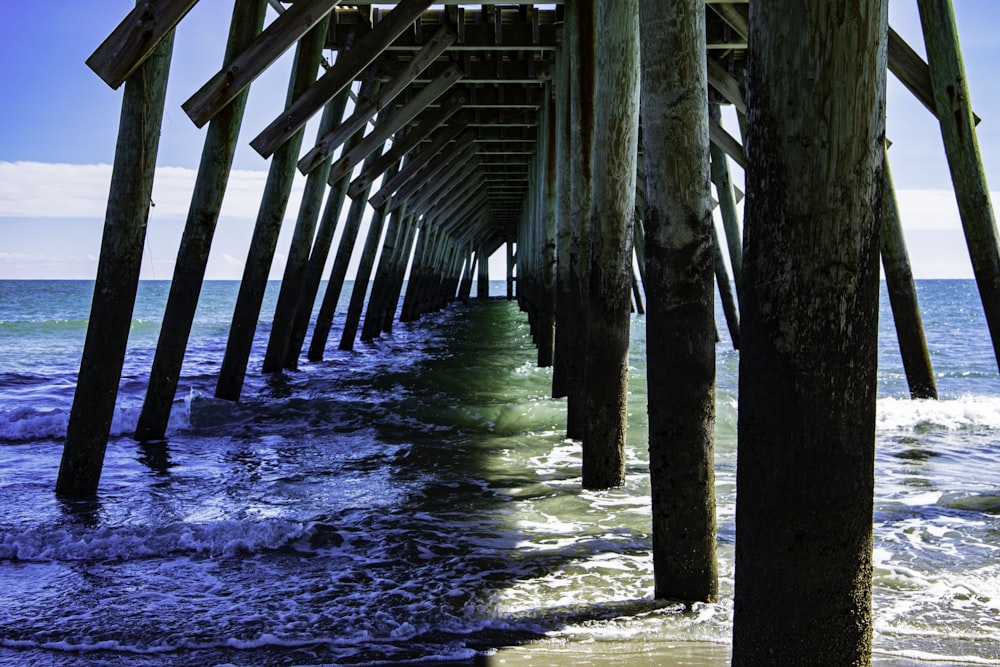 a view of the ocean under a wooden pier