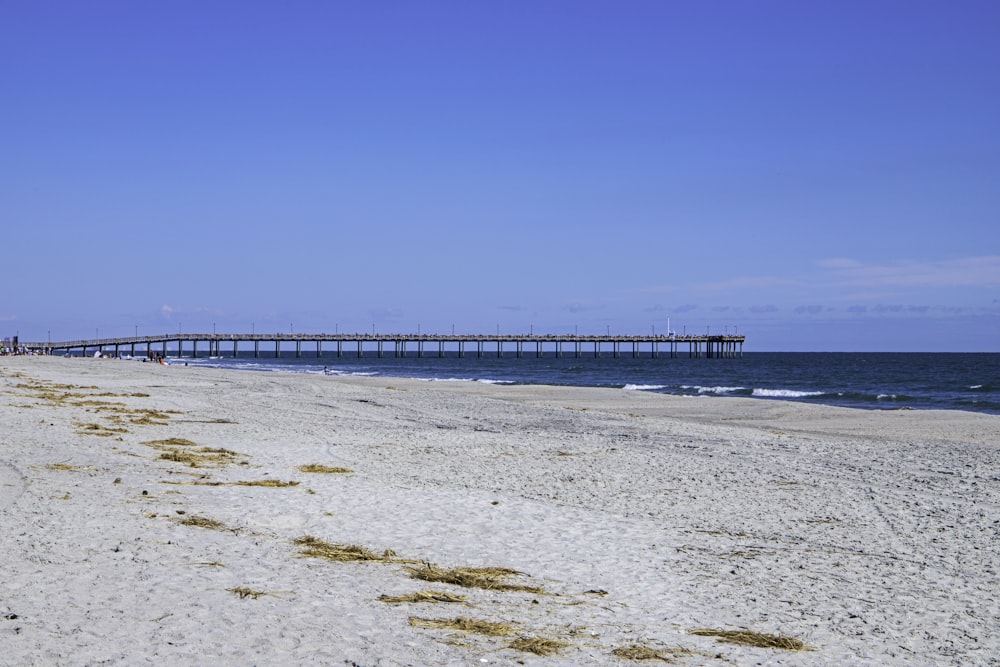 a beach with a pier in the distance