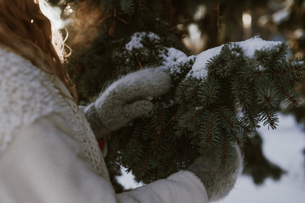 a woman is holding a pine tree in the snow