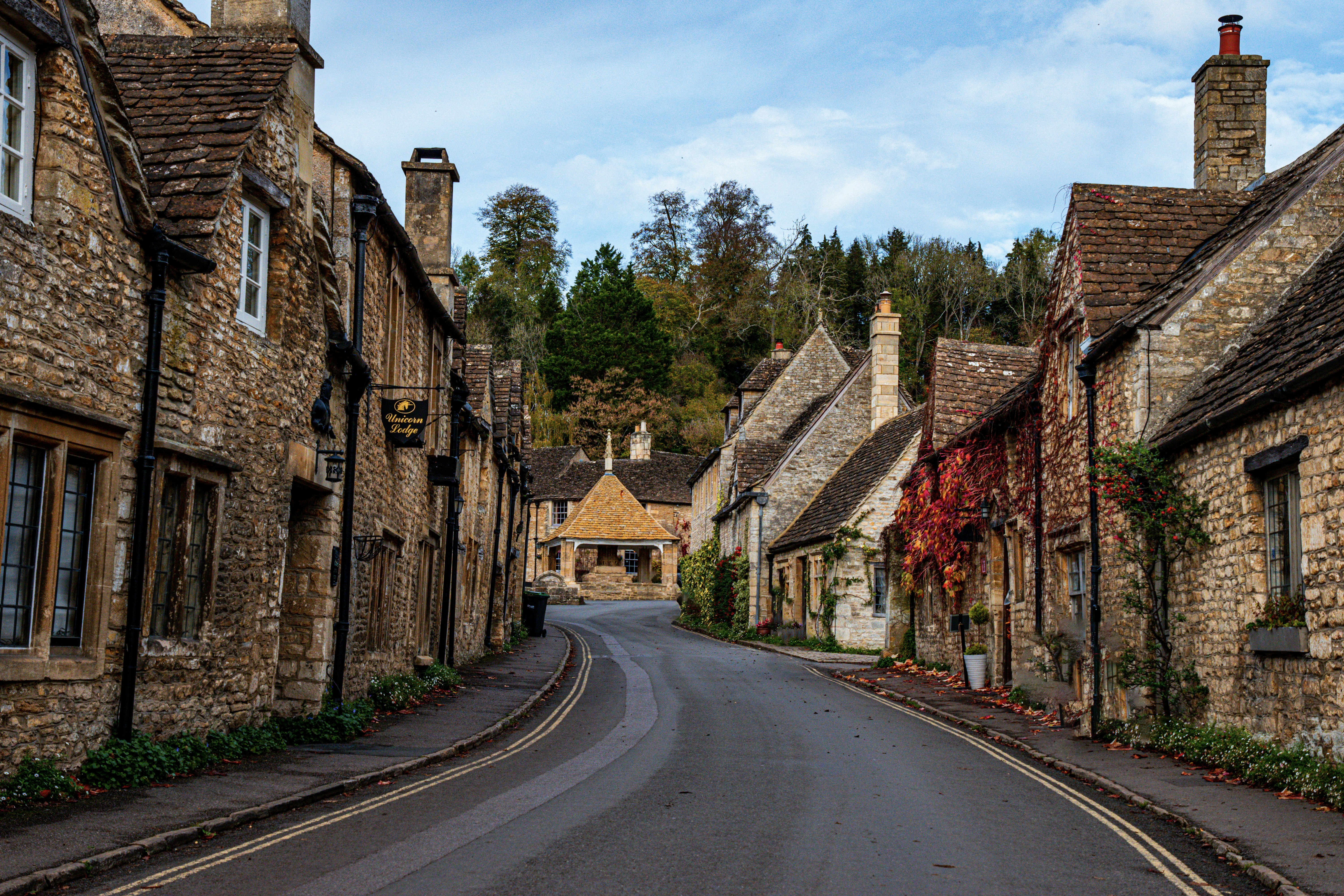 a street lined with stone buildings next to a forest