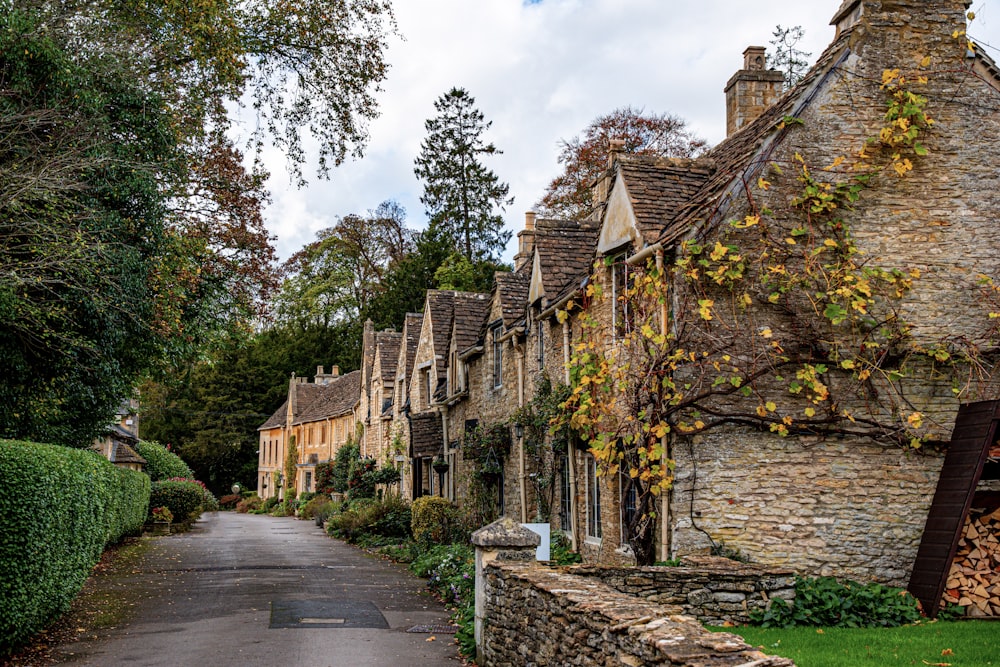 a street lined with stone buildings next to a lush green forest