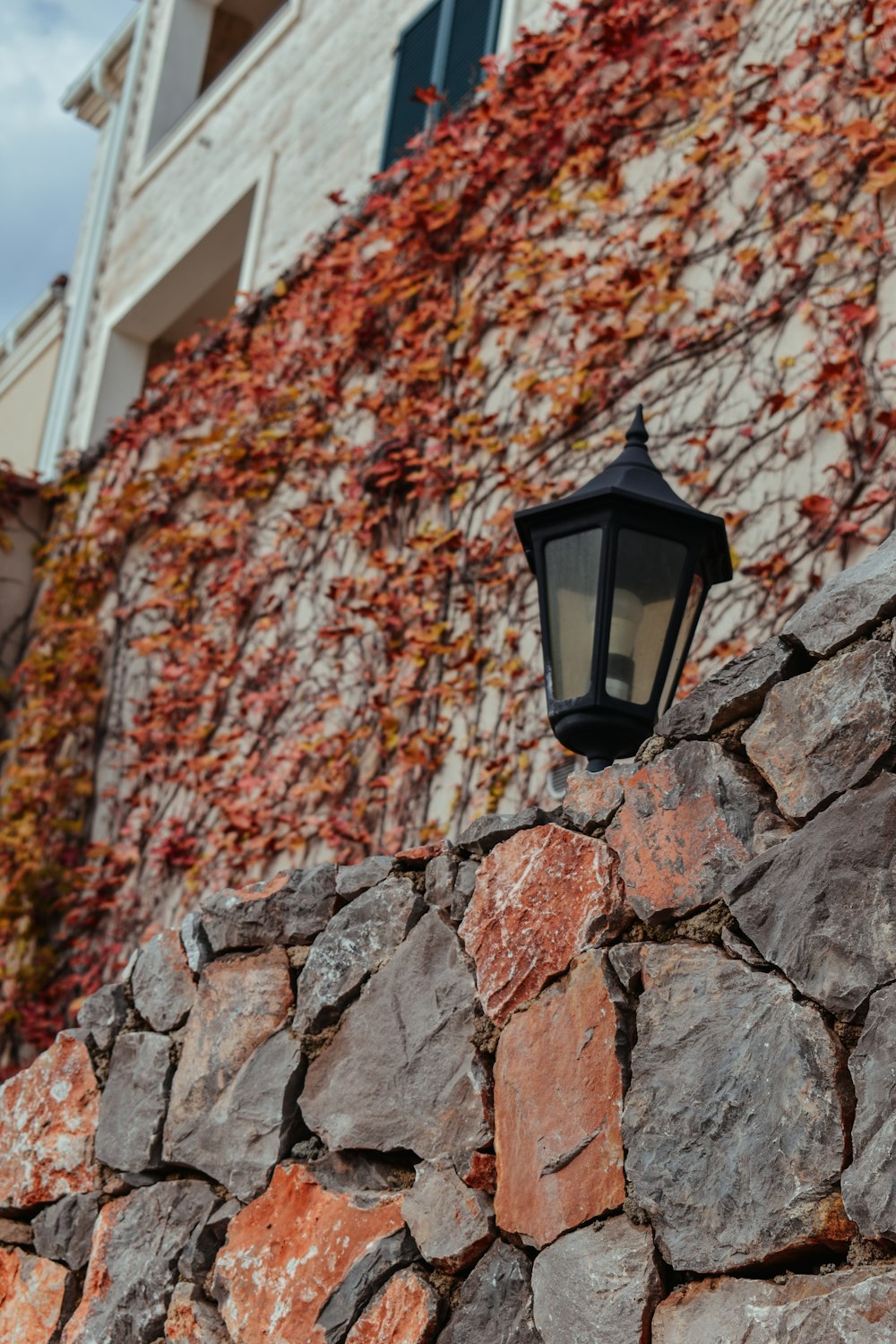 a lamp on a stone wall in front of a building