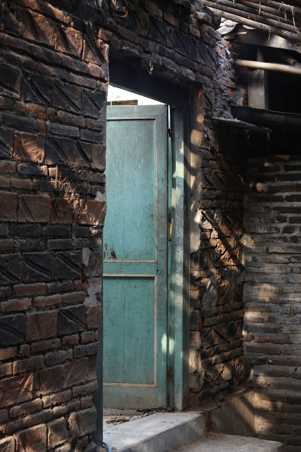 a green door is open in a brick building