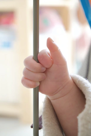 Happy baby reaching for food from a bowl held steady by the nidofirme clamp during mealtime.
