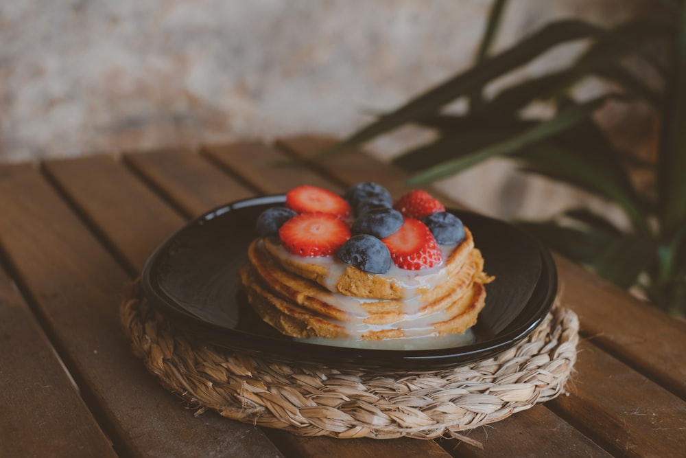 a stack of pancakes with strawberries and blueberries on top