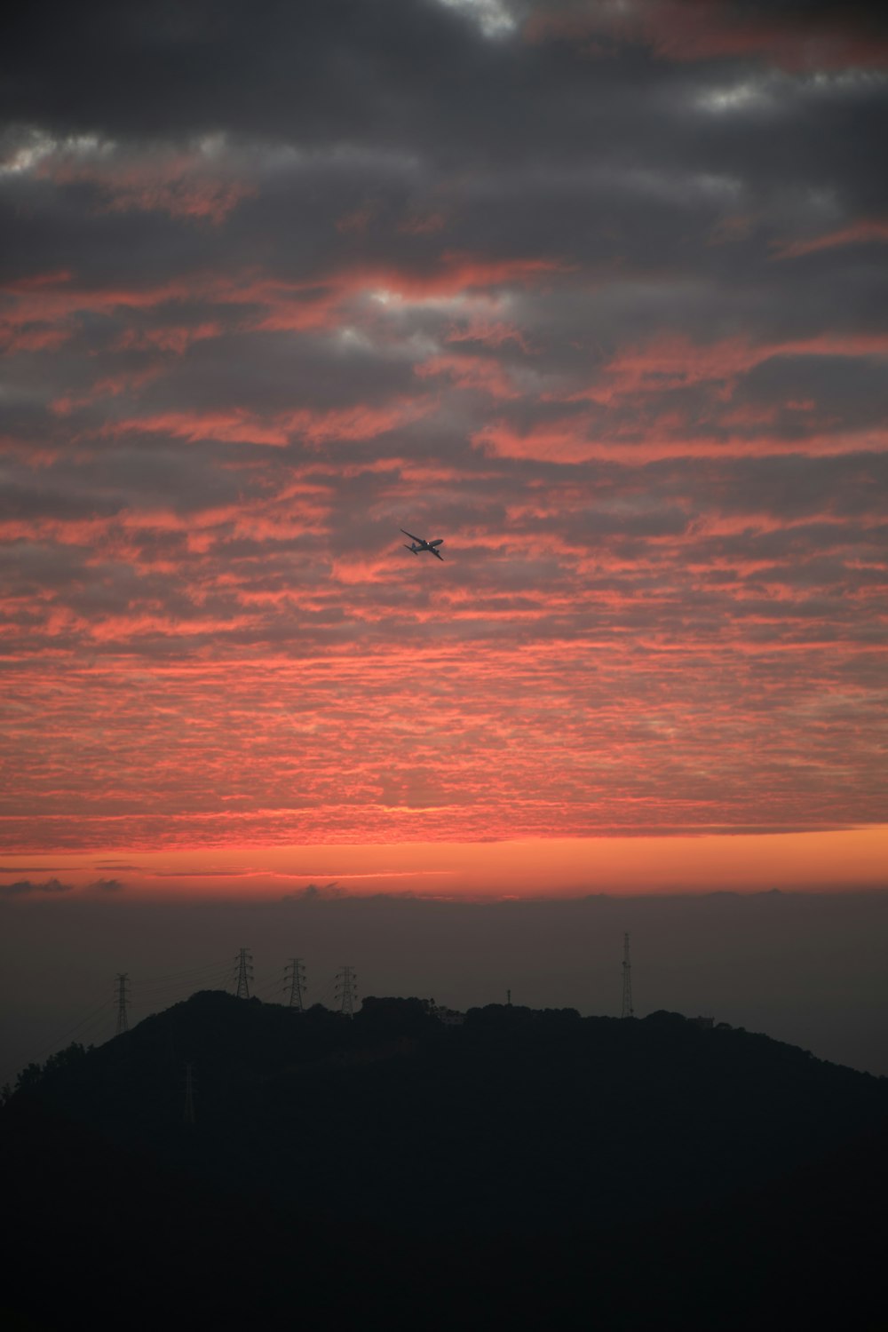 a plane flying in the sky at sunset
