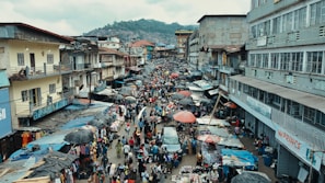 A bustling Lagos street market alive with colorful stalls and busy shoppers under a bright sky