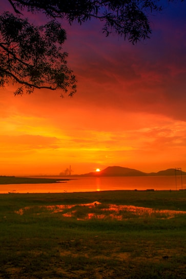 A vibrant acrylic painting of a sunset over a serene lake, showcasing rich oranges and purples.