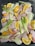 Raw chicken pieces are arranged on a baking tray, surrounded by cut fennel stalks and orange wedges. The colors of the ingredients are fresh and vibrant, with the oranges and fennel adding a contrasting brightness to the pink chicken.