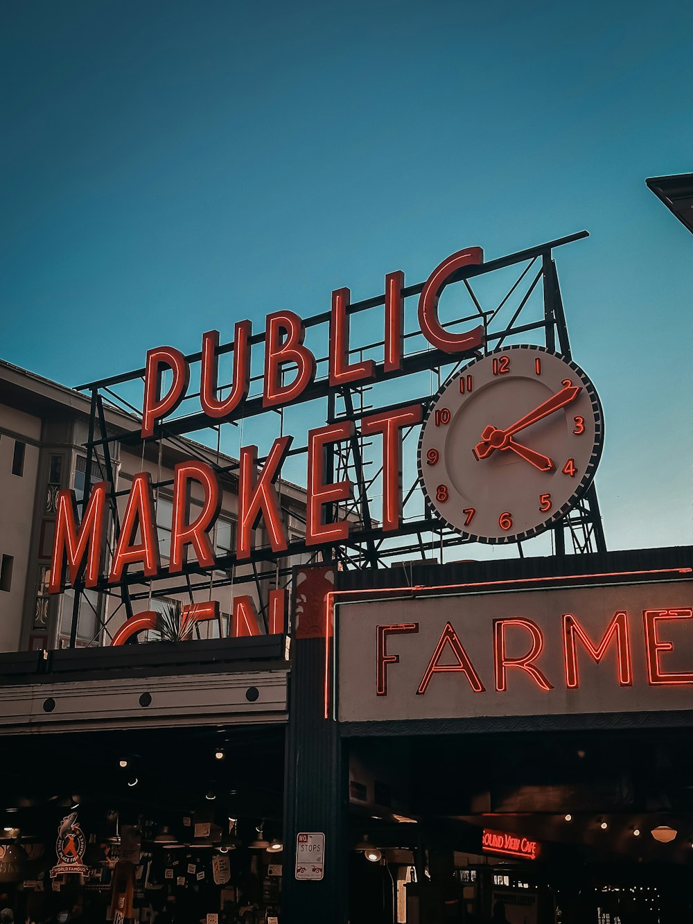 a large clock on top of a sign for a farmers market